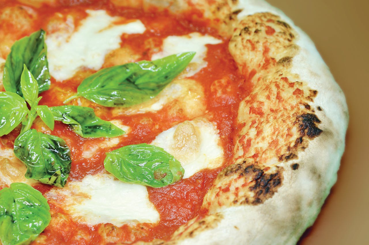 Close-up of a freshly baked Neapolitan pizza with mozzarella and basil leaves.